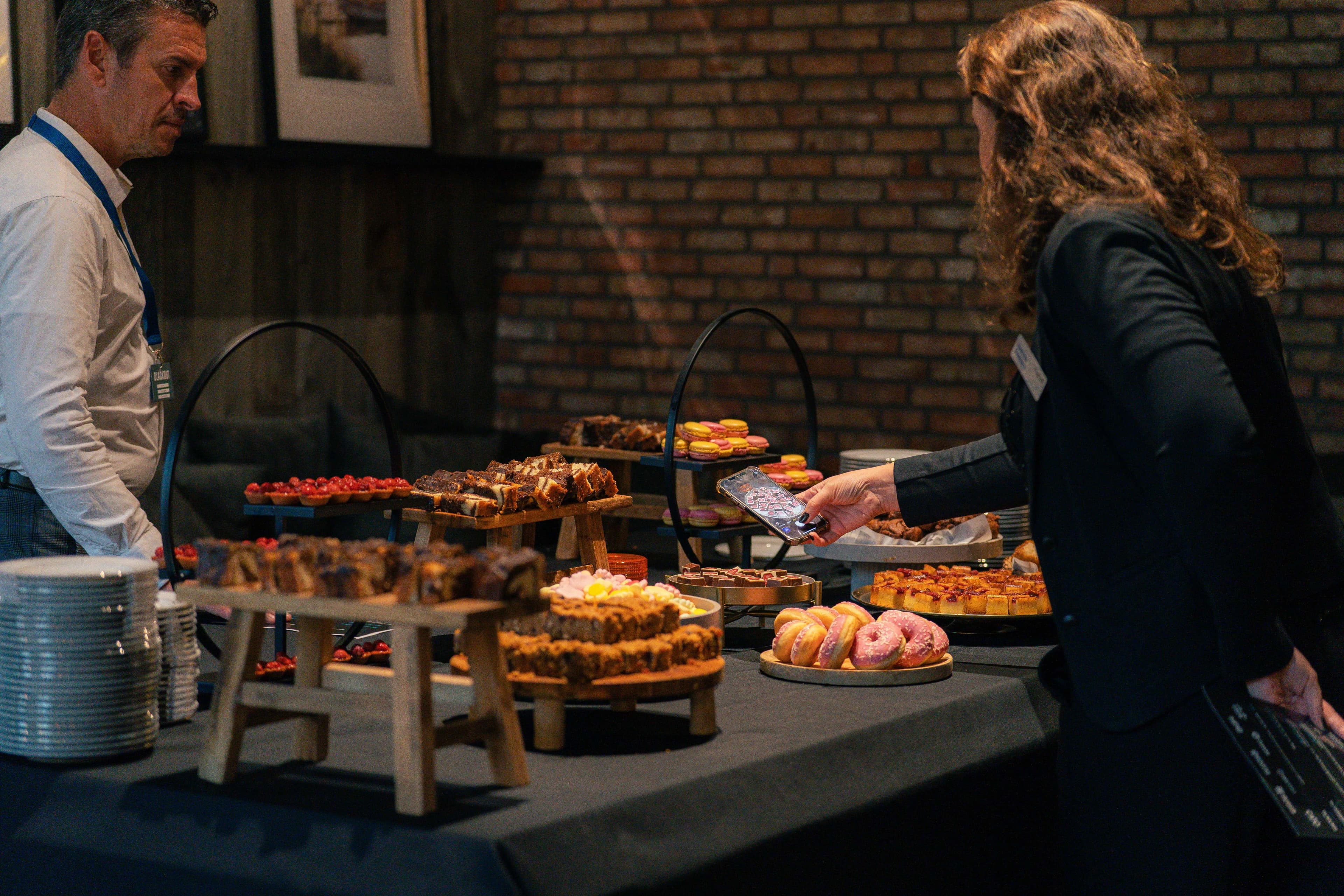 Gasten bij buffet met zoete bites en gebak - bedrijfscatering